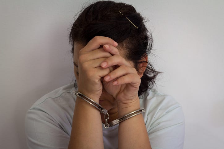 Desperate criminal woman sitting on the floor in handcuffs