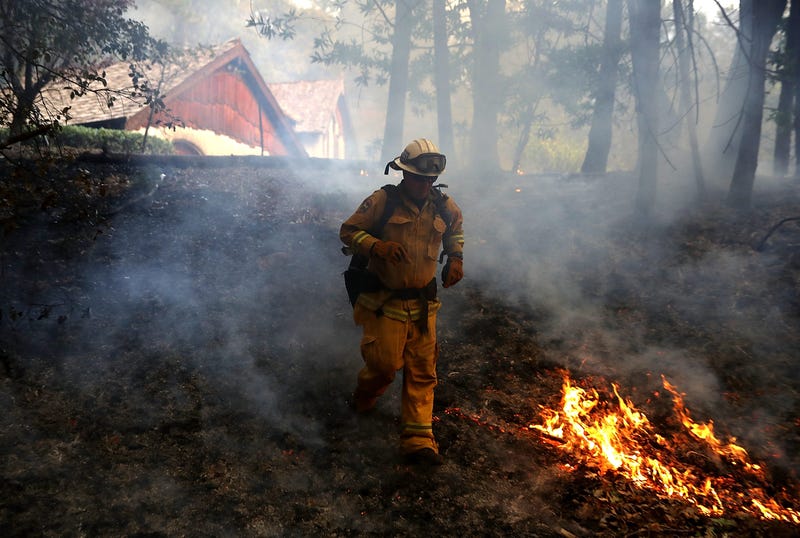 : A CalFire chief runs past burning grass during a firing operation while battling the Tubbs Fire on October 12, 2017 near Calistoga, California.