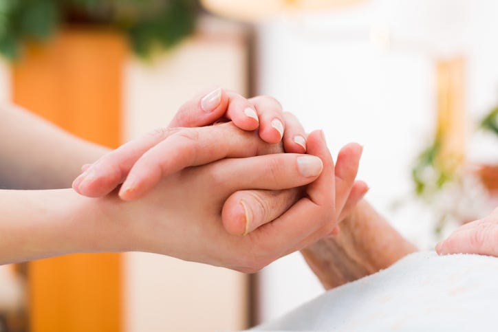 A caregiver holding a person's hand. 