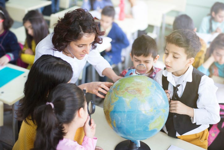 female teacher and students looking the globe 