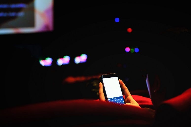 Man using cell phone in a movie theater