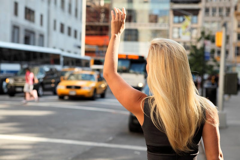 Blonde woman flags down taxi cab in New York City