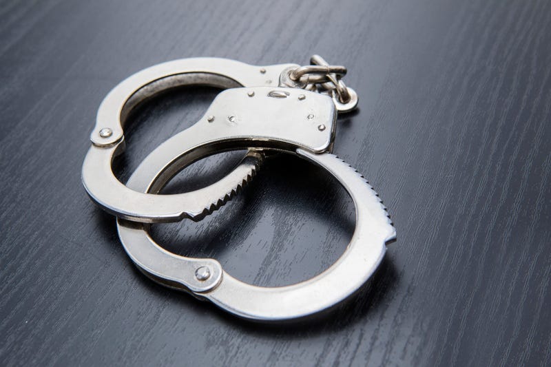 Closeup of silver handcuffs detaining crime prisoners. Shot on the wooden table