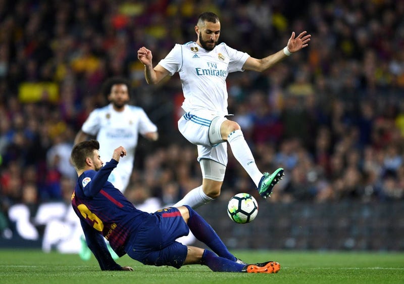 BARCELONA, SPAIN - MAY 06: Karim Benzema of Real Madrid is challenged by Gerard Pique of Barcelona during the La Liga match between Barcelona and Real Madrid at Camp Nou on May 6, 2018 in Barcelona, Spain.