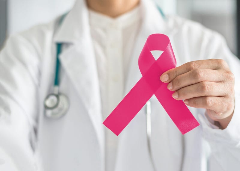 doctor holding pink ribbon representing breast cancer awareness