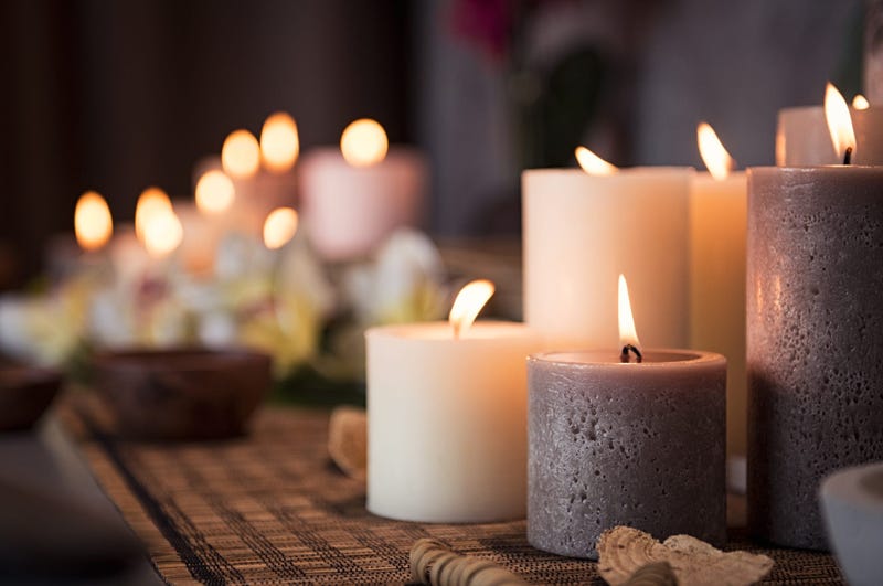 Closeup of burning candles spreading aroma on table in a spa room. Beautiful composition with grey and white candles for spa treatment. Zen and relax concept.