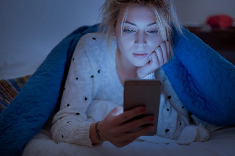 Girl looking at phone in bed before falling asleep