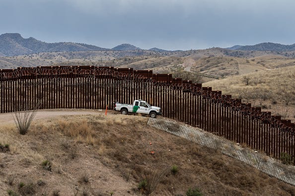 A Border Patrol officer sits inside his car as he guards the US/Mexico border fence, in Nogales, Arizona