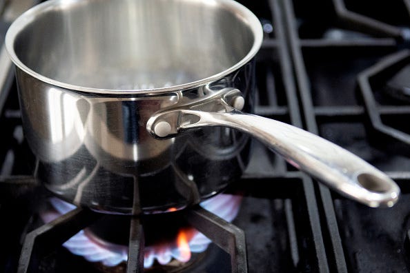 A pot with boiling water sits on flames burning on a natural gas burning stove