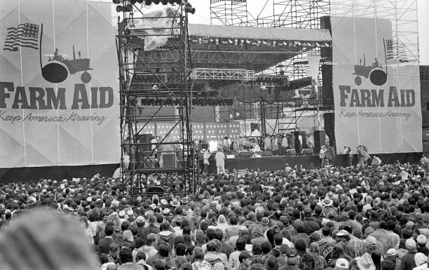 View, over the crowd, of American Country musician Willie Nelson performs onstage at the debut Farm Aid benefit festival, Champaign, Illinois, September 22, 1985. The festival celebrates 40 years in Minneapolis this Saturday night.