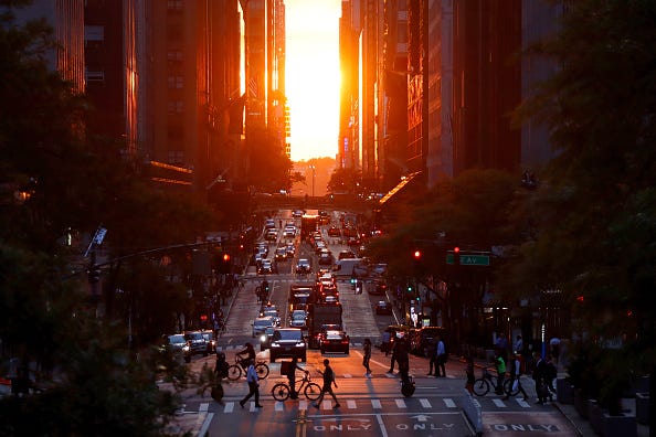 People walk across 42nd Steet as the sun sets on June 6, 2022, in New York City.