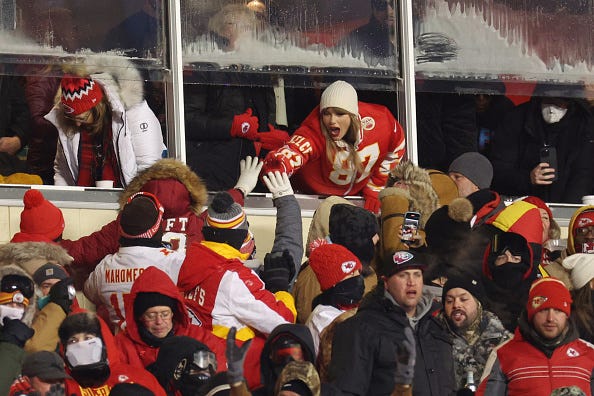 KANSAS CITY, MISSOURI - Taylor Swift celebrates with fans during the AFC Wild Card Playoffs between the Miami Dolphins and the Kansas City Chiefs at Arrowhead Stadium on January 13, 2024