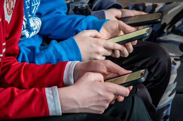 Teenage boys looking at their smartphone screens