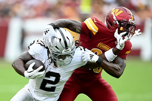 Ashton Jeanty #2 of the Las Vegas Raiders stiff arms Quan Martin #20 of the Washington Commanders during the second quarter at Northwest Stadium on September 21, 2025 in Landover, Maryland.