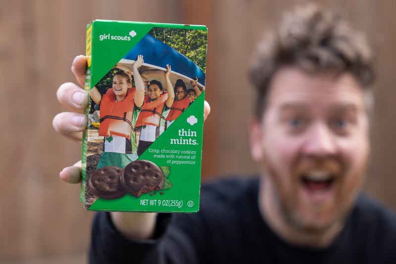 Blurry background man holds up box of Thin Mint cookies!