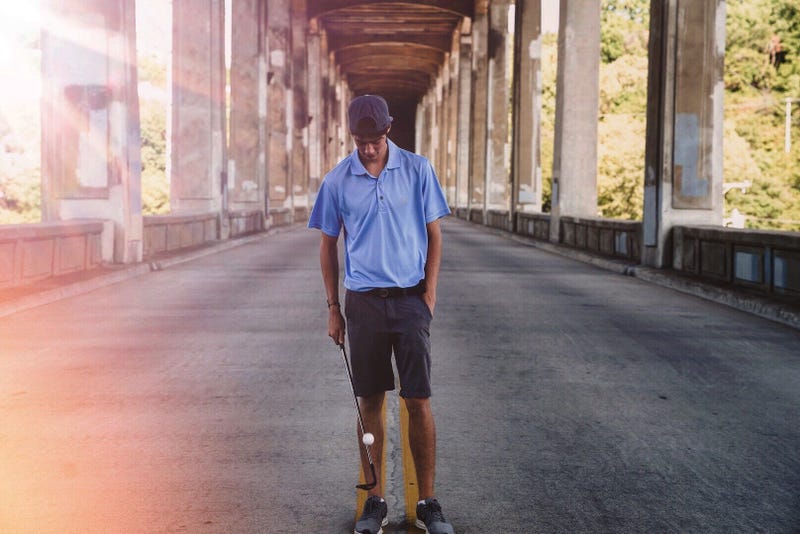 young man balancing ball on golf club