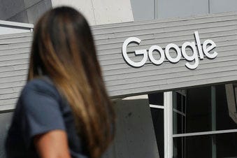 FILE - In this Sept. 24, 2019, file photo, a woman walks below a Google sign on the campus in Mountain View, Calif. New Mexico is suing Google over allegations that the tech company is illegally collecting personal data. (AP Photo/Jeff Chiu, File)