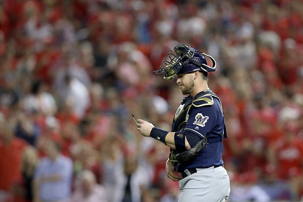 Milwaukee Brewers C Yasmani Grandal looks at his notes during a mound visit.