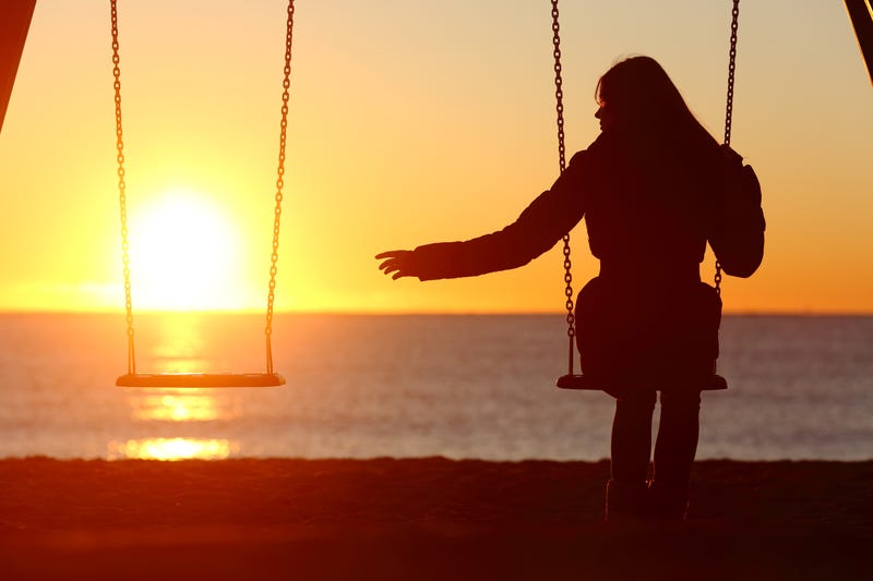 grieving woman on swing at sunset