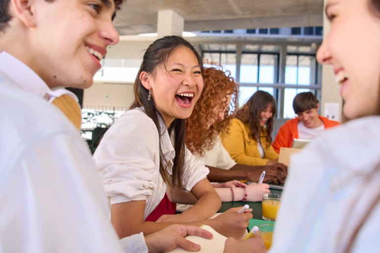 HighSchool students laughing at a cafeteria table