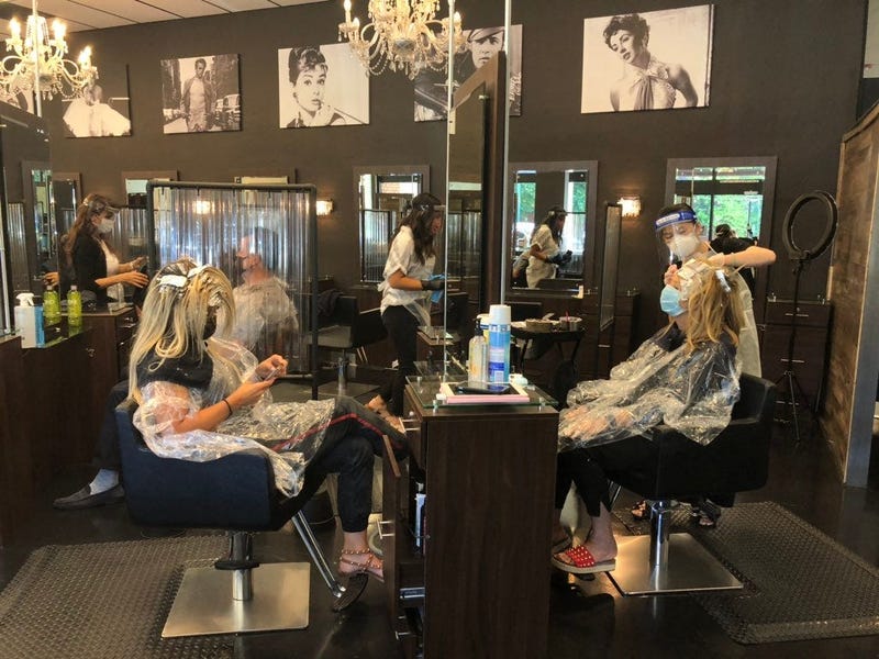 Stylists wear shields and PPE in working with clients at this salon in Walnut Creek.
