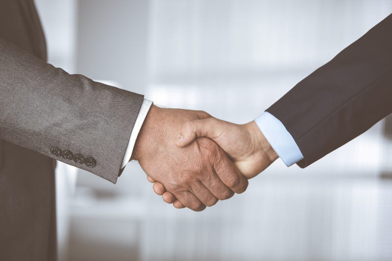 Business people in office suits standing and shaking hands, close-up