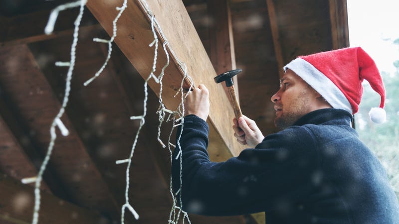 Man in Santa hat hangs up a string of lights