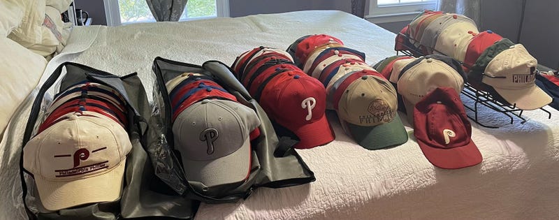 Phillies hats on a bed.