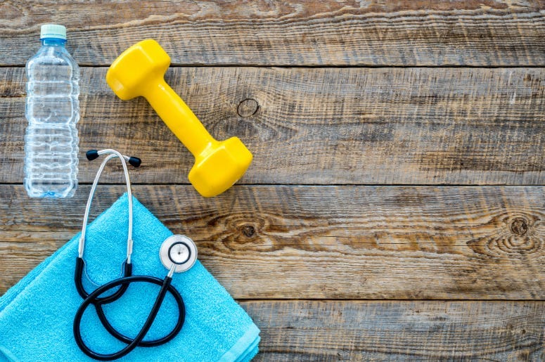 Sport and health. Fitness. Dumbbells and stethoscope on wooden background top view copyspace