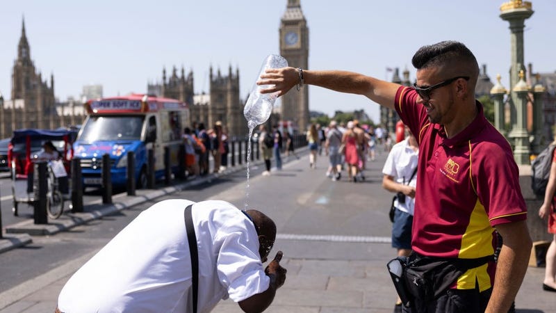 A man pours water over a friends head on Westminster Bridge on July 19, 2022 in London, United Kingdom.