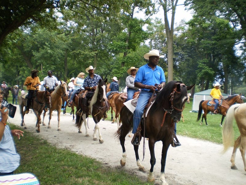 African American man atop horse in park