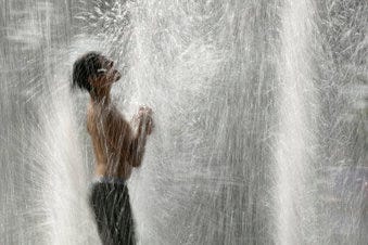 FILE - In this July 18, 2019, file photo, a boy plays in a fountain to cool off as temperatures approach 100 degrees Fahrenheit (38 Celsius) in Kansas City, Mo. (AP Photo/Charlie Riedel, File)
