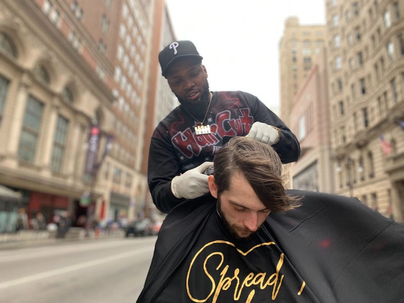 Brennon Jones gives a free haircut in Center City, on the median at Broad and Walnut Streets.
