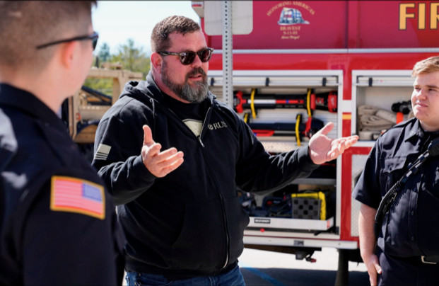 Reg McCutcheon speaks to first responders in front of a fire truck.
