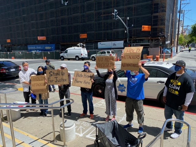 Protestors hold up signs outside the Hall of Justice calling for an end to violence against Asian Americans.