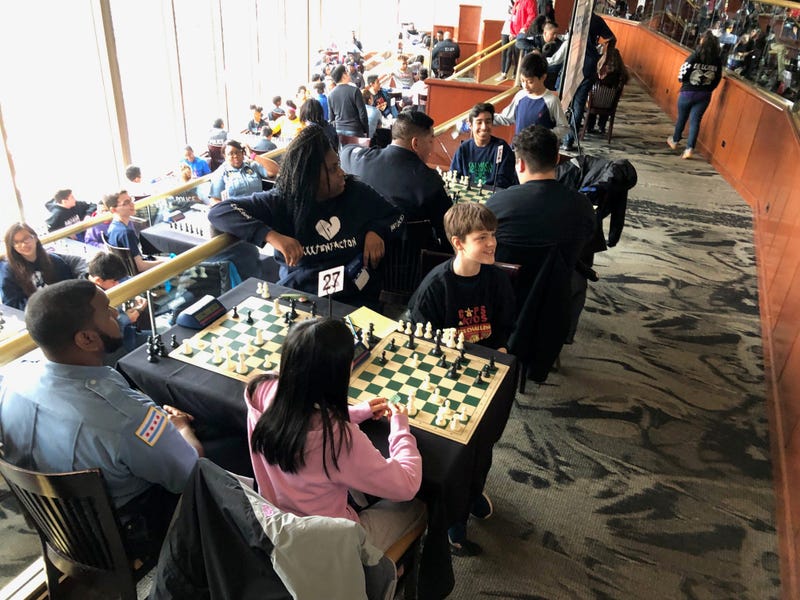 In the Stadium Club at Sox Park, with a view of the field, on a rainy day better suited for indoor activities than baseball, 150 CPS students and a couple dozen CPD officers were playing chess.