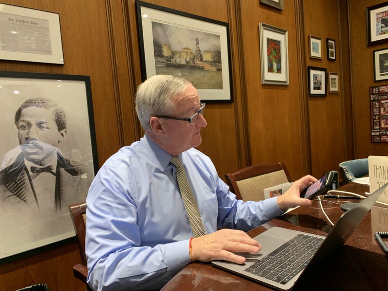 Philadelphia Mayor Jim Kenney multitasking in his office. Behind him, a portrait of civil rights activist Octavius Catto.