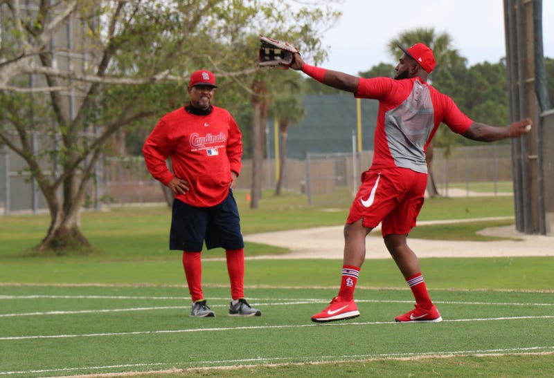 Outfielder Marcell Ozuna works with coach Jose Oquendo on a throwing drill.