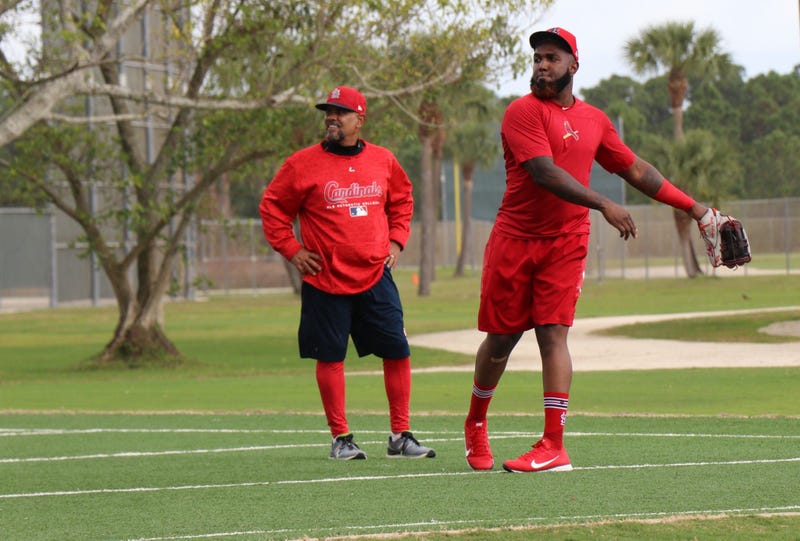 Outfielder Marcell Ozuna works with coach Jose Oquendo on a throwing drill.