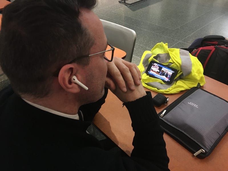 A man watches Michael Cohen testify before the House Oversight Committee on his iPhone while grabbing breakfast at the Comcast Center, Feb. 27, 2019.