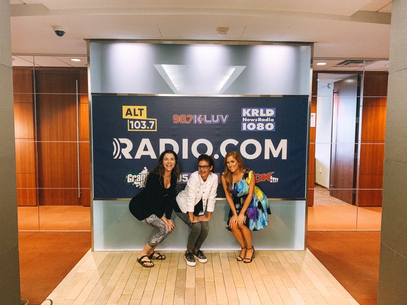 Tyler Dawn, Sybil Summers, and Hilary Kennedy pose in front of RADIO.COM sign