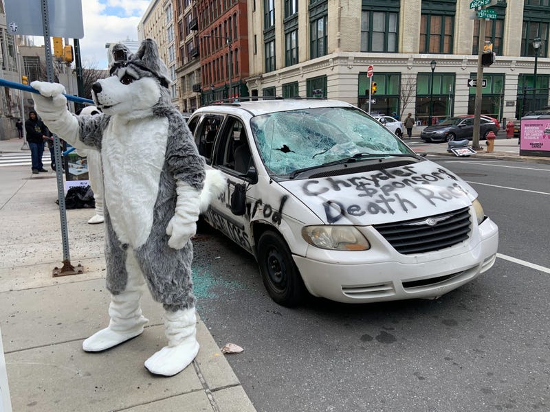 A protester dressed in a dog costume helps destroy a Chrysler minivan, as a statement regarding the company's support of the Iditarod sled dog race.