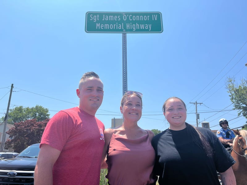 Sgt. James O’Connor IV's family members James, Terri and Kelsey pose in front of a stretch of Knights Road in Northeast Philadelphia that was renamed after him.