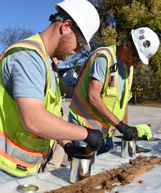 two men in work vests testing soil samples