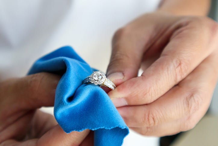 person cleaning a ring with a soft towel