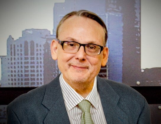WWJ overnight anchor Jim Matthews in front of a backdrop featuring the Detroit skyline
