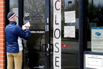 FILE - In this April 30, 2020 file photo, a man writes information in front of Illinois Department of Employment Security in Chicago. (AP Photo/Nam Y. Huh, File)