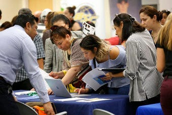 FILE - In this Sept. 18, 2019, file photo job applicants looks at jobs available at Florida International University during a job fair in Miami.  (AP Photo/Lynne Sladky, File)