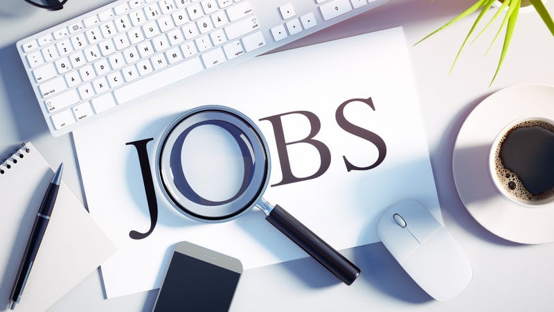Top view of a white desktop with magnifying glass over the word JOB