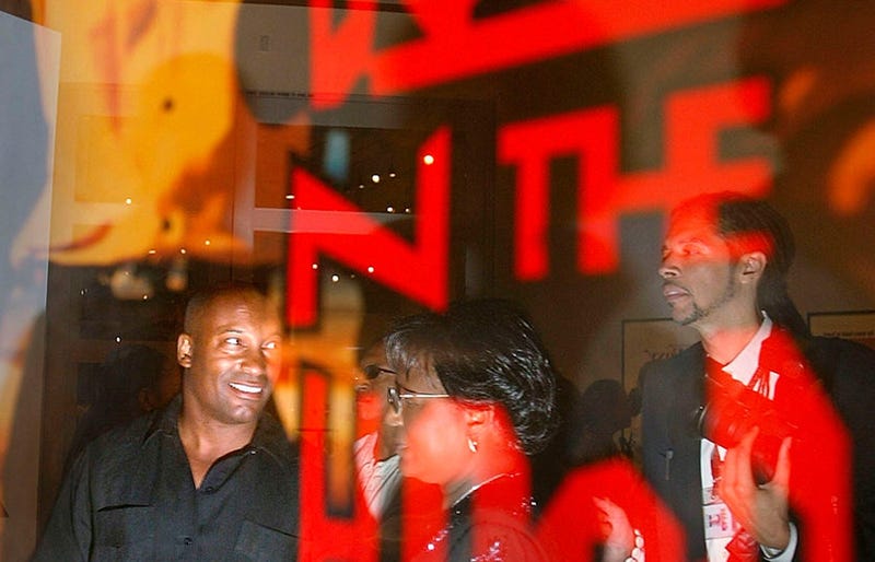 Director John Singelton (l) is reflected in a poster for his movie Boyz n the hood as he visits an exibition of African American film posters at the California African American Museum August 8, 2003 in Los Angeles. 